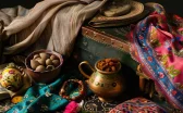 a colorful silk scarf draped over a suitcase filled with traditional persian pottery, spices, and a guidebook to iran.